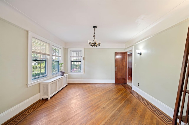 unfurnished room featuring hardwood / wood-style floors and a notable chandelier