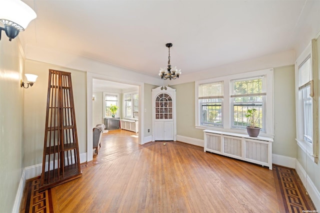 interior space with radiator heating unit, a notable chandelier, and wood-type flooring