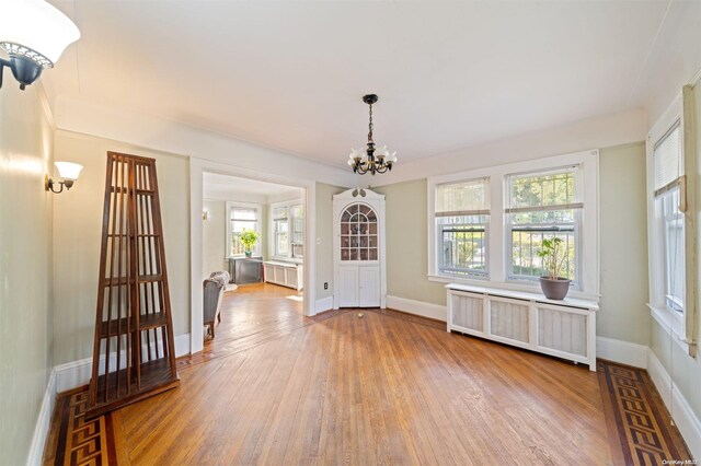 193-32 Foothill Ave, Holliswood, NY 11423 - unfurnished dining area featuring radiator heating unit, wood finished floors, a chandelier, and baseboards