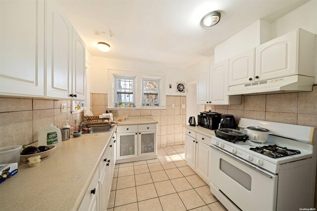 193-32 Foothill Ave, Holliswood, NY 11423 - kitchen with gas range gas stove, under cabinet range hood, light tile patterned floors, a sink, and white cabinetry