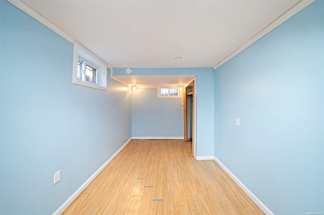 basement featuring light wood-type flooring and crown molding