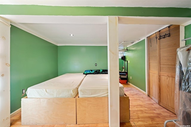 bedroom featuring a closet, light hardwood / wood-style flooring, and crown molding