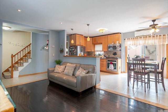 living room with a wall mounted air conditioner, ceiling fan, and wood-type flooring