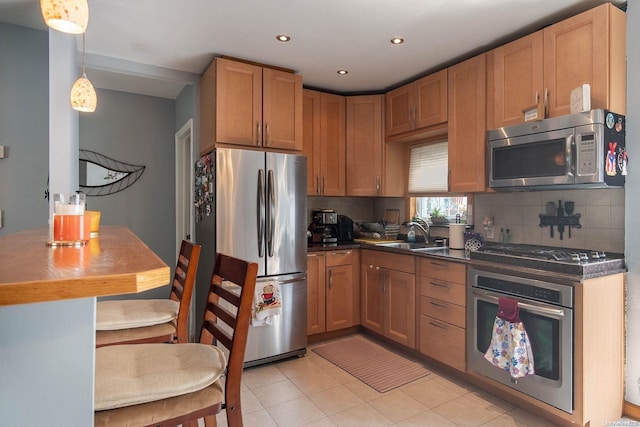 kitchen with sink, backsplash, pendant lighting, light tile patterned floors, and appliances with stainless steel finishes