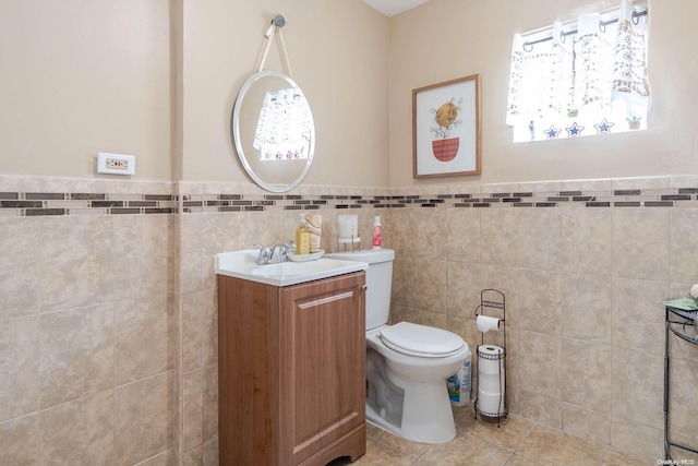 bathroom with toilet, vanity, tile patterned floors, and tile walls