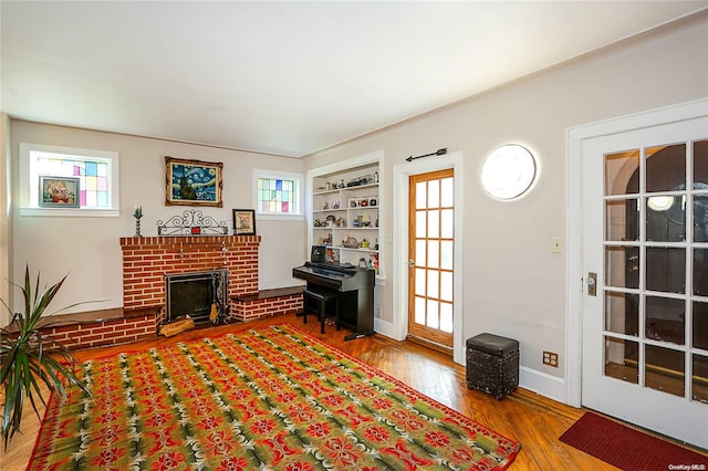 living room featuring hardwood / wood-style floors, built in shelves, and a fireplace