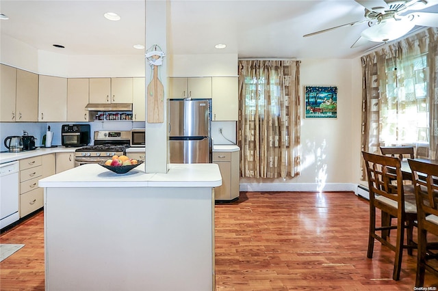 kitchen with ceiling fan, a kitchen island, stainless steel appliances, and hardwood / wood-style flooring