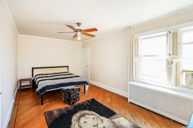 bedroom with radiator, ceiling fan, crown molding, and hardwood / wood-style flooring