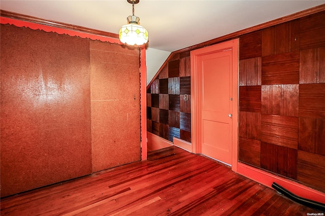 spare room with hardwood / wood-style flooring, vaulted ceiling, and wooden walls