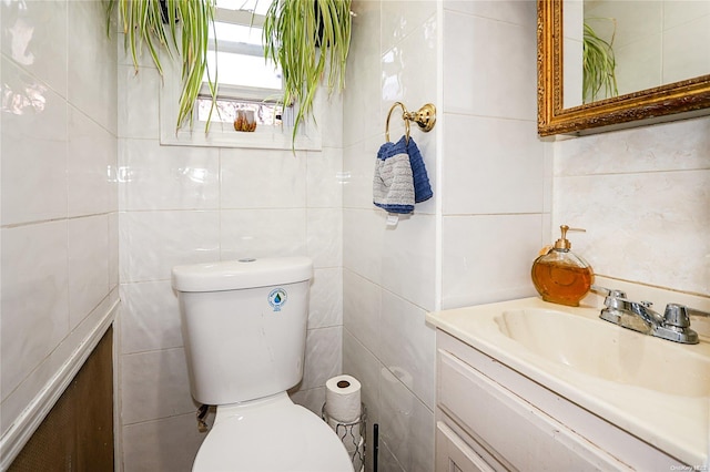 bathroom with vanity, toilet, and tile walls