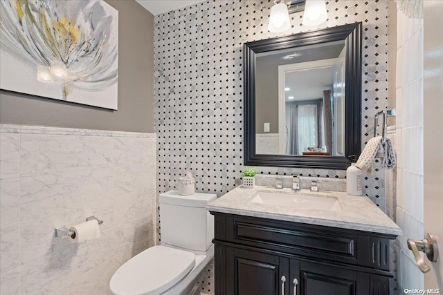 bathroom with vanity, toilet, and tile walls