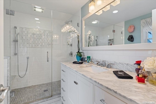 bathroom featuring vanity, an enclosed shower, backsplash, and tile walls