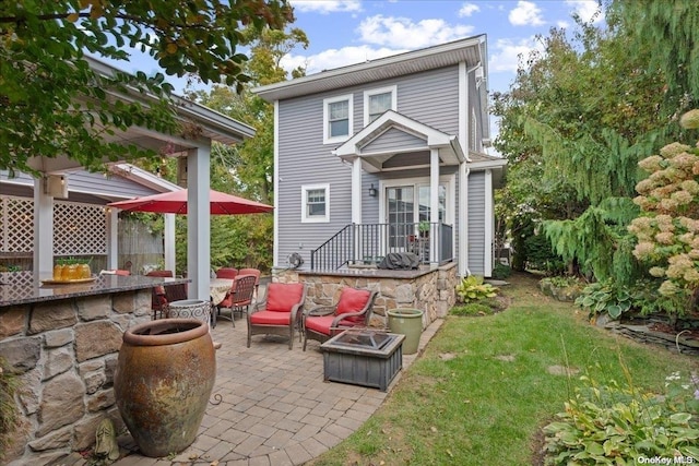 rear view of house with a lawn, a patio area, and a fire pit