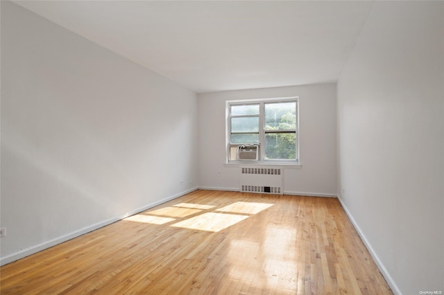 empty room with cooling unit, light wood-type flooring, and radiator