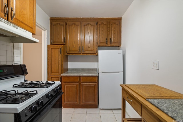 kitchen featuring decorative backsplash, white appliances, and light tile patterned floors