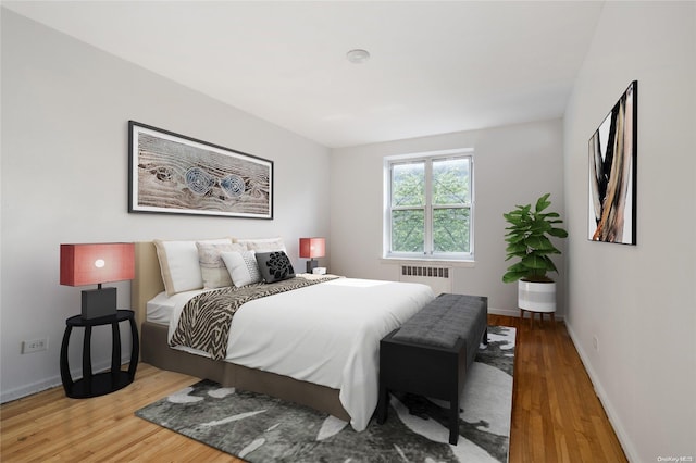 bedroom with radiator heating unit and wood-type flooring