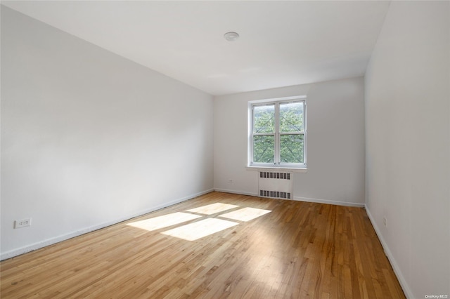 unfurnished room featuring radiator and light hardwood / wood-style flooring