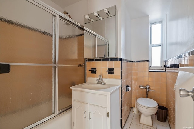 full bathroom with tile patterned flooring, toilet, shower / bath combination with glass door, vanity, and tile walls