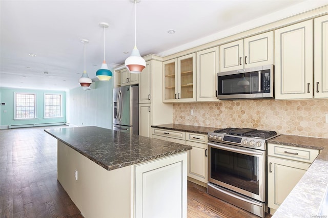 kitchen with a center island, cream cabinets, hanging light fixtures, light wood-type flooring, and appliances with stainless steel finishes