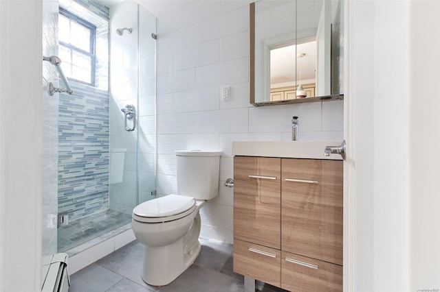 bathroom featuring a baseboard heating unit, tile patterned floors, toilet, vanity, and tile walls