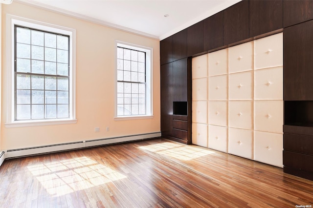 unfurnished bedroom with light hardwood / wood-style floors, crown molding, multiple windows, and a baseboard heating unit