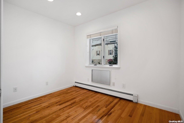 empty room featuring a baseboard radiator and hardwood / wood-style flooring