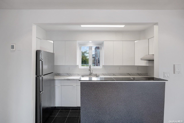 kitchen featuring stainless steel refrigerator, sink, backsplash, white cabinets, and dark tile patterned flooring