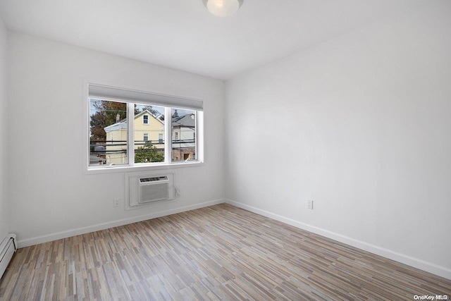 empty room featuring baseboard heating, light hardwood / wood-style flooring, and a wall mounted AC