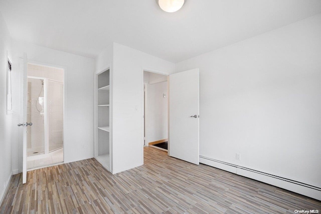 unfurnished bedroom featuring light hardwood / wood-style floors and a baseboard heating unit