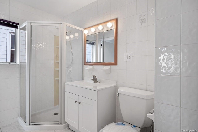 bathroom with walk in shower, vanity, toilet, and tile walls