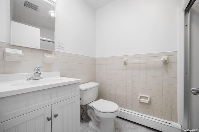 bathroom featuring baseboard heating, vanity, tile walls, and toilet