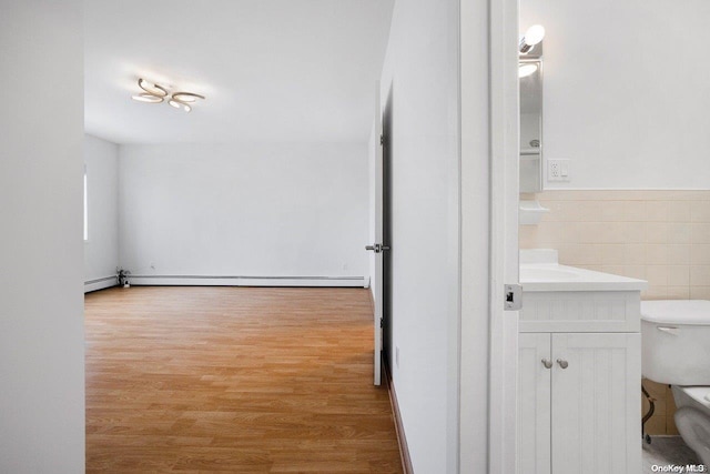 bathroom with vanity, a baseboard heating unit, tile walls, hardwood / wood-style floors, and toilet