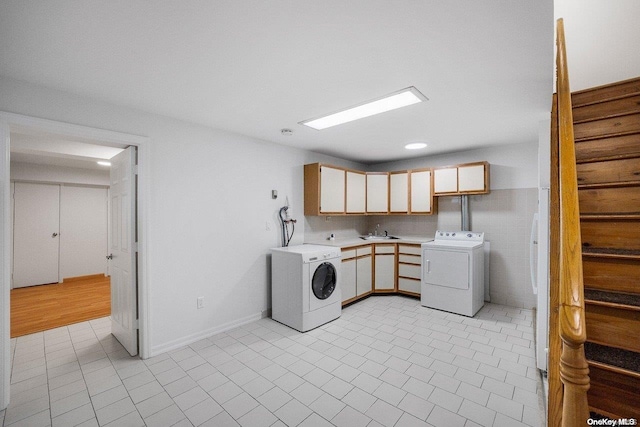 laundry area with washer and clothes dryer, sink, light tile patterned floors, and cabinets