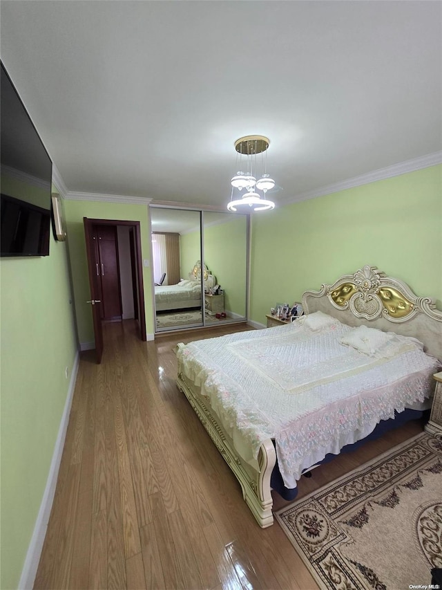 bedroom with light wood-type flooring, an inviting chandelier, and crown molding