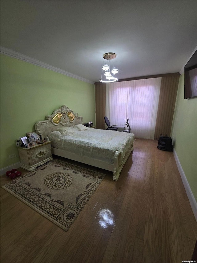 bedroom with dark hardwood / wood-style flooring, a notable chandelier, and ornamental molding