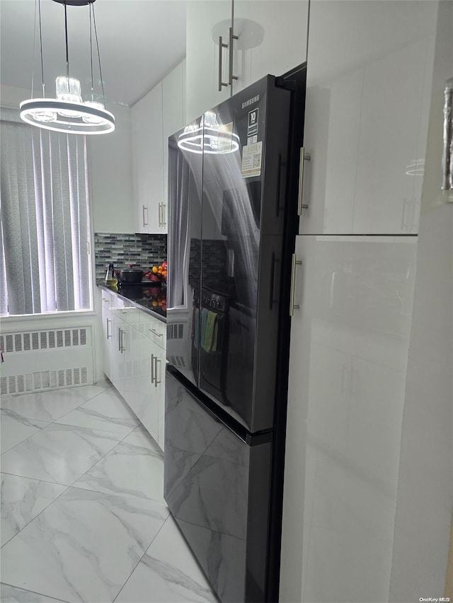 kitchen featuring white cabinets, decorative backsplash, stainless steel fridge, decorative light fixtures, and radiator heating unit