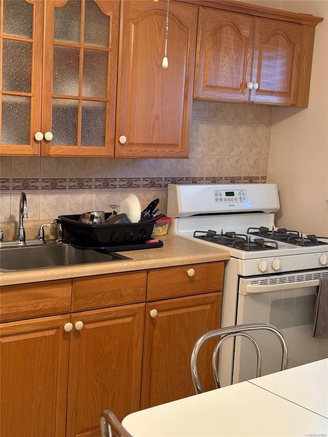 76-04 Springfield Blvd Unit 1, Bayside, NY 11364 - kitchen with gas range gas stove, decorative backsplash, a sink, glass insert cabinets, and light countertops