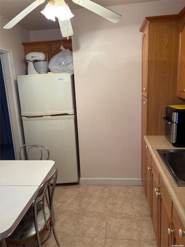 kitchen featuring ceiling fan, sink, light tile patterned floors, and white refrigerator