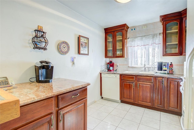 kitchen featuring dishwasher, light tile patterned floors, light stone counters, and sink