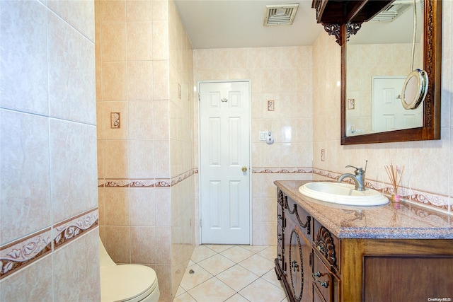 bathroom with tile patterned flooring, vanity, toilet, and tile walls