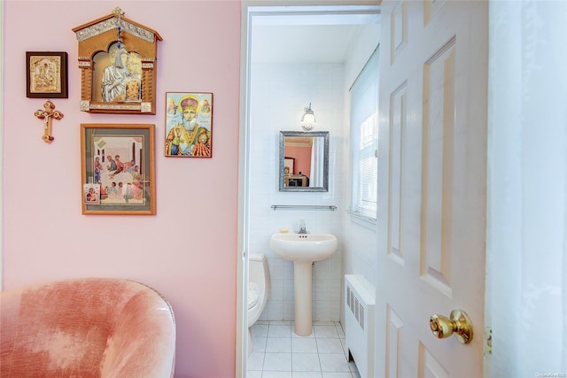 bathroom featuring radiator, sink, tile patterned flooring, toilet, and tile walls