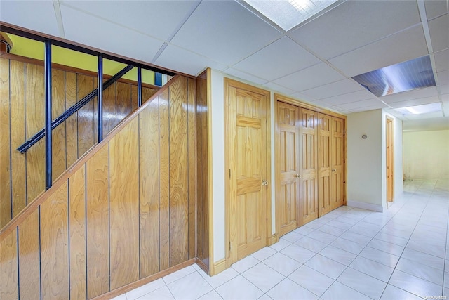 hallway with light tile patterned floors and a paneled ceiling