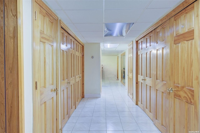 hallway with a drop ceiling and light tile patterned flooring