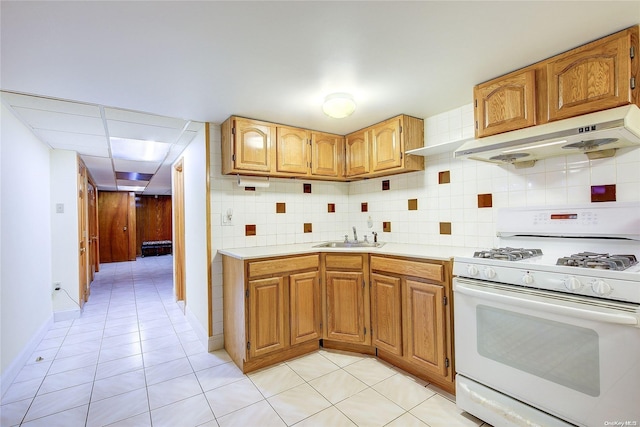 kitchen featuring decorative backsplash, light tile patterned flooring, sink, and gas range gas stove