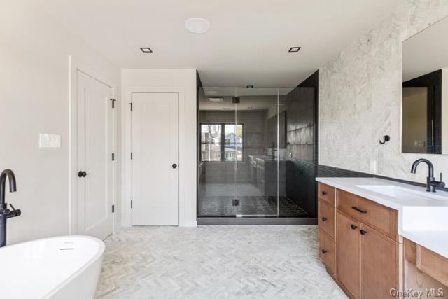 full bath with a shower stall, a freestanding tub, and vanity