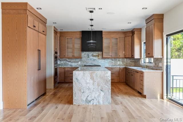 kitchen with a center island, brown cabinets, decorative backsplash, and light wood-style floors