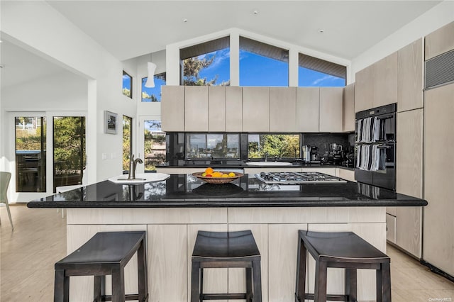 kitchen featuring stainless steel gas stovetop, a breakfast bar, dark stone countertops, tasteful backsplash, and a kitchen island