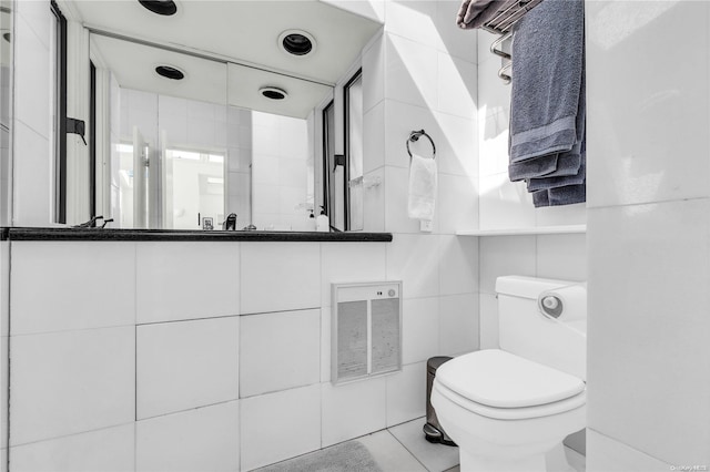 bathroom with toilet, tile patterned floors, and tile walls