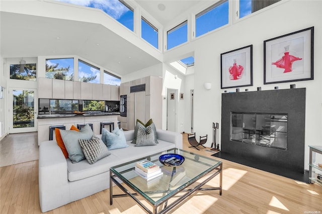 living room featuring high vaulted ceiling and light hardwood / wood-style floors