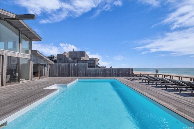 view of swimming pool with a deck with water view and a beach view